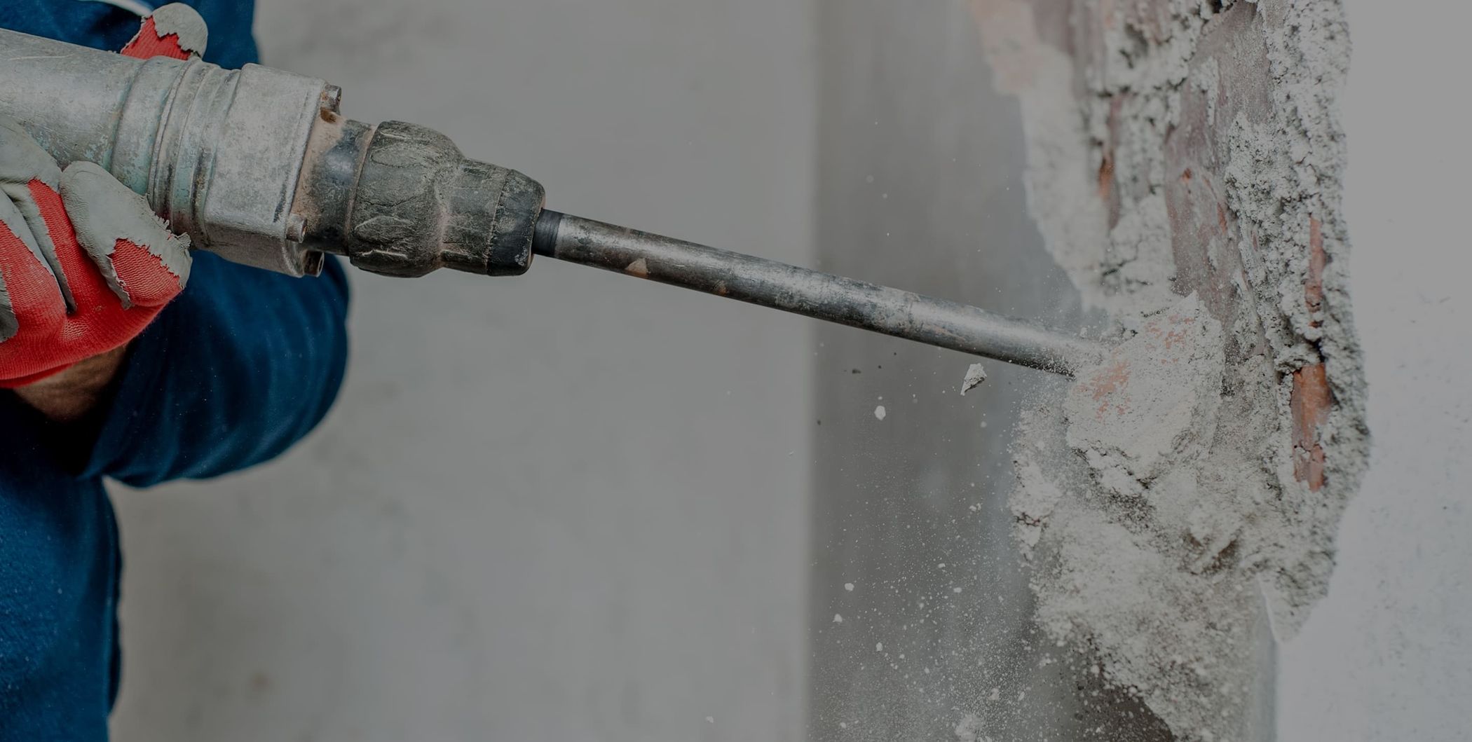 Arbeiter stemmt mit einem Bohrhammer eine Wand auf – Abbruch- und Stemmarbeiten im Innenbereich