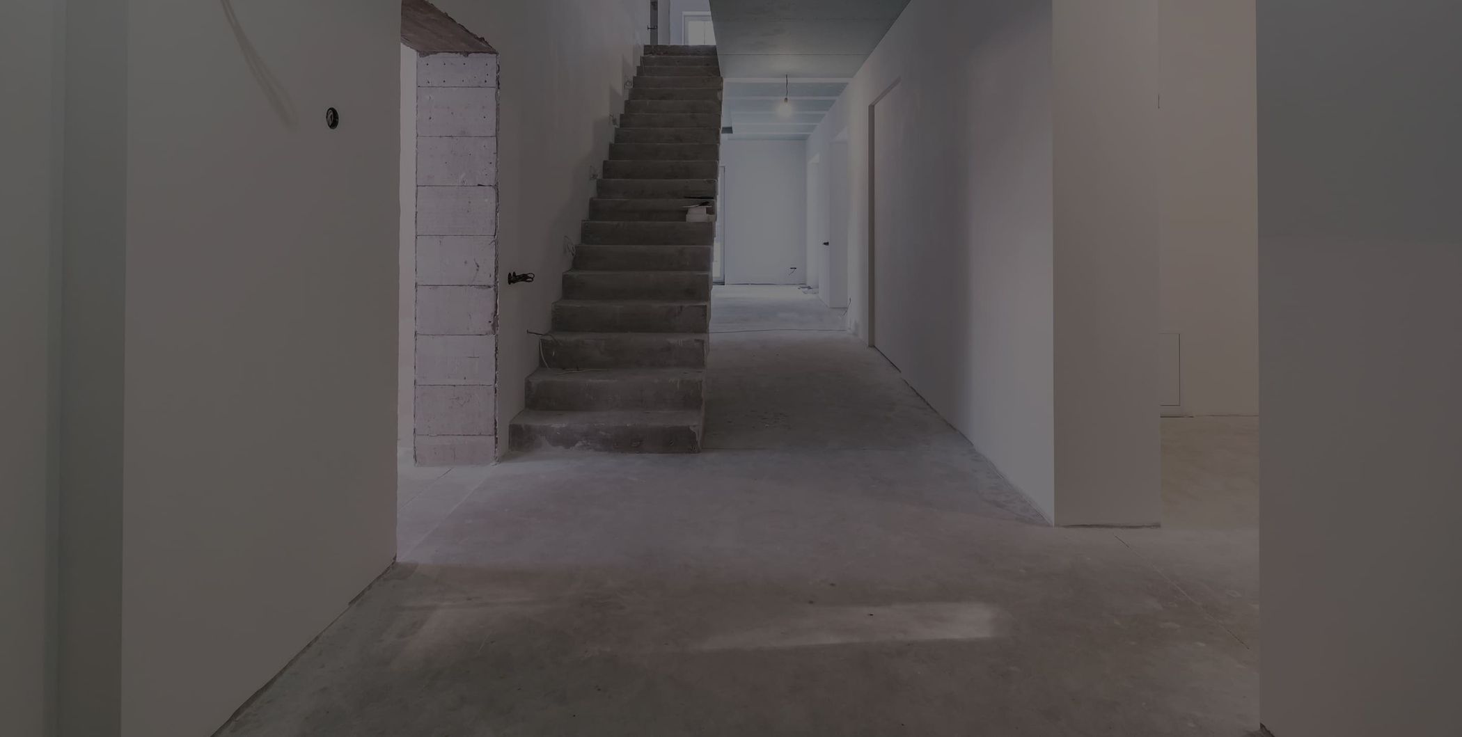 Flur eines Rohbaus mit Betontreppe im Hintergrund – Neubau im Rohbauzustand